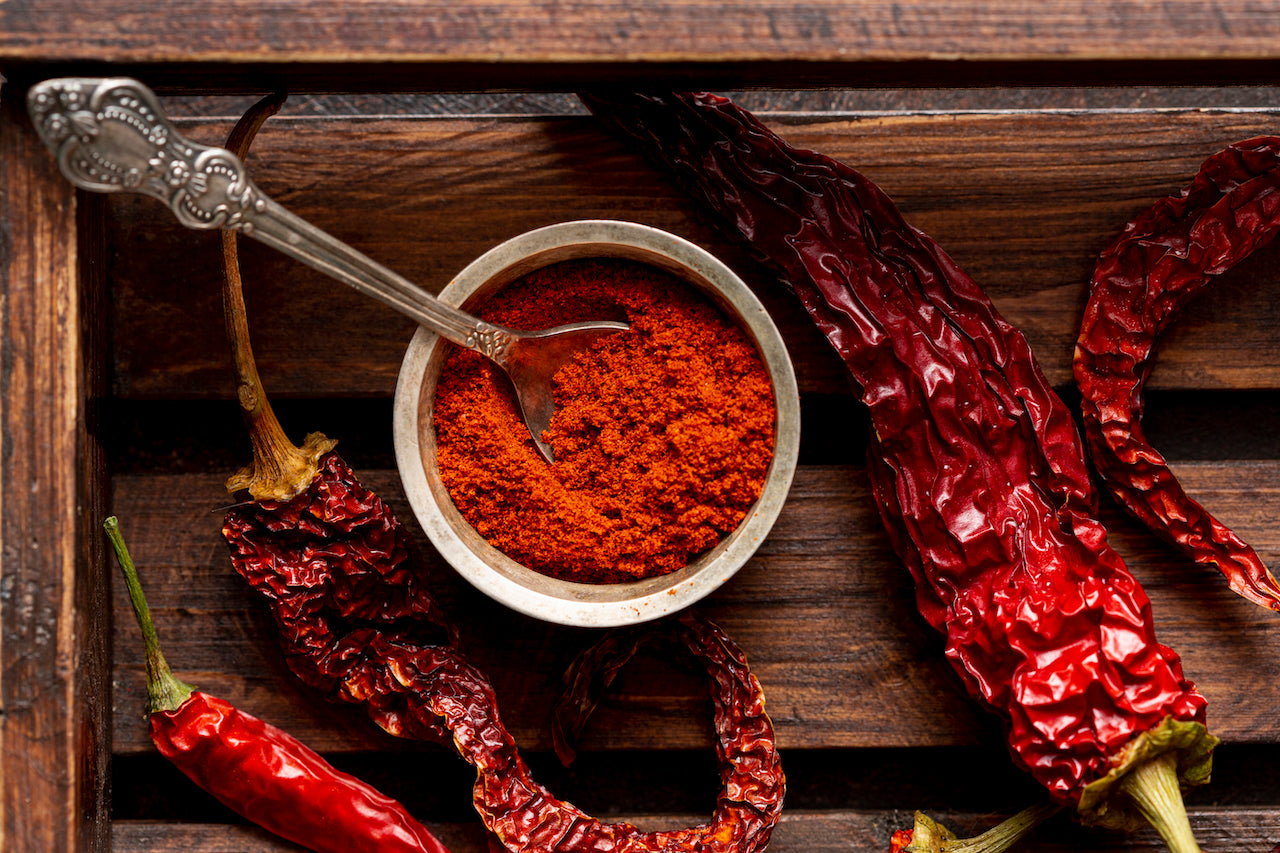 top view of chili peppers and paprika powder on a wooden tray