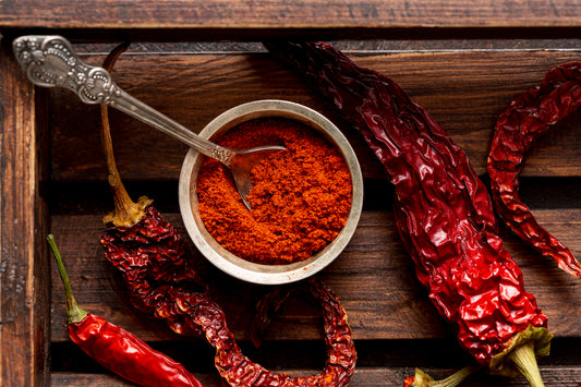 top view of chili peppers and paprika powder on a wooden tray